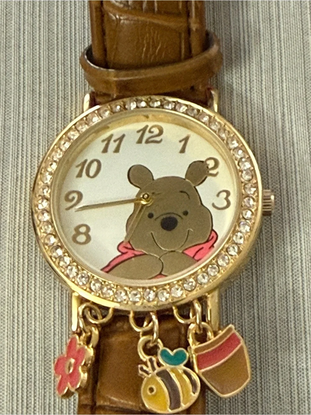 Disney Winnie the Pooh watch features a crystal-bezel dial and dangling charms o